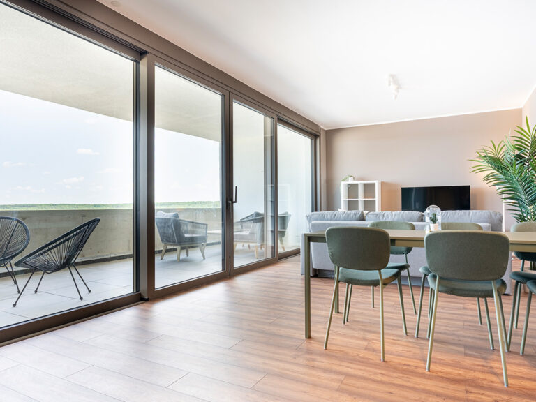 Essbereich in Apartment 3 und 7 mit Tisch, vier Stühlen, im Hintergrund Blick auf die Loggia.